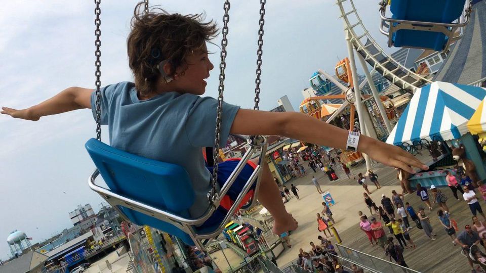 A child rides on an amusement park swing set. MOONLIGHT SONATA: DEAFNESS IN THREE MOVEMENTS AT REELABILITIES FILM FESTIVAL